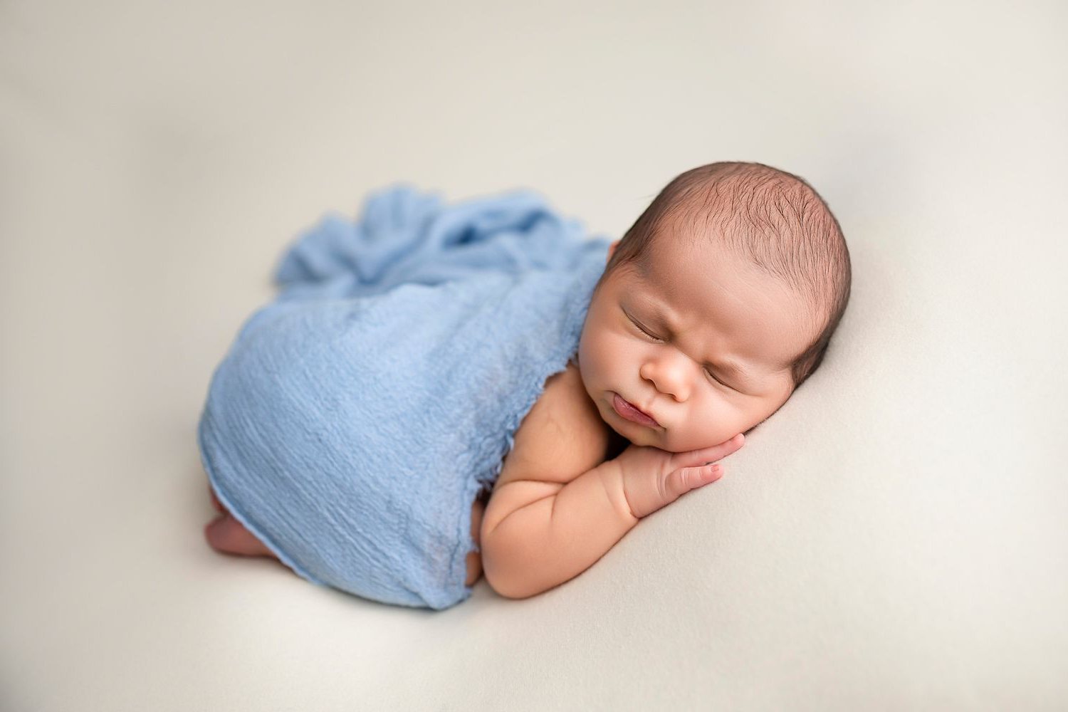 Sleeping newborn wrapped in soft blue, photographed at Lilia Photography studio in Lewisville, Texas